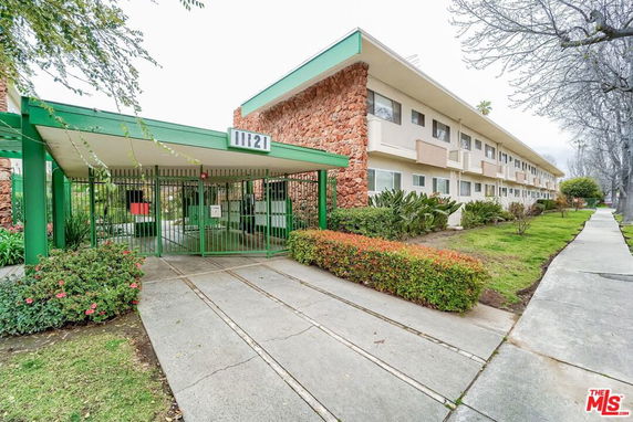 Front view of a multi-story apartment building with a gated entrance.