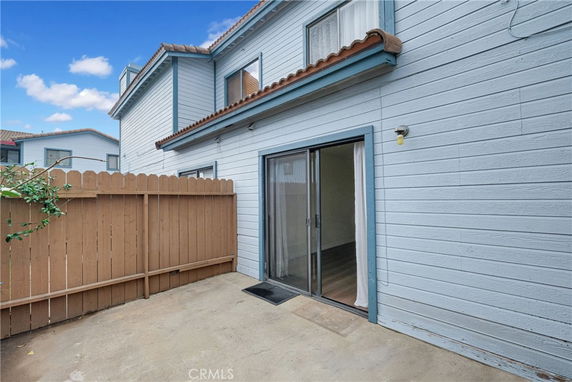 Exterior view of a two-story house with sliding glass door and wooden fence.