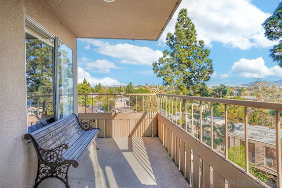 Balcony view overlooking a residential area with trees and distant buildings.