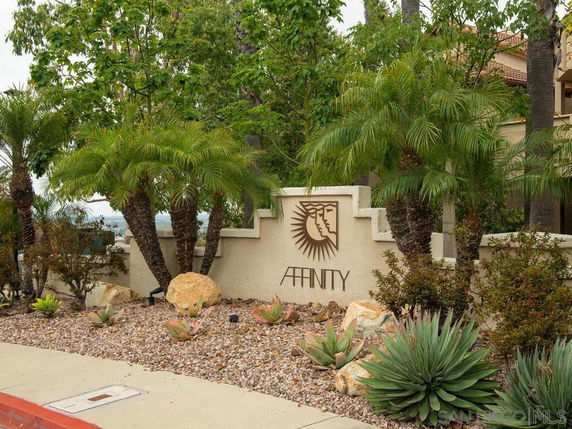Front view of a decorative stone wall with the word 'Affinity' and a stylized sun and face design.