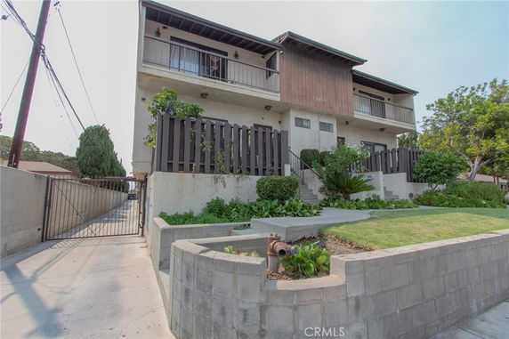 Front view of a two-story building with balconies and a gated driveway.