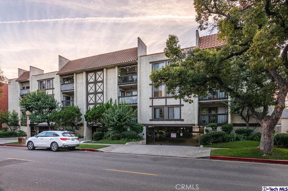 Front view of a multi-story residential building with balconies and a tiled roof.