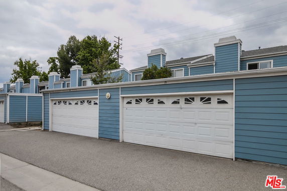 Front view of a row of townhouses with blue siding and white garage doors.