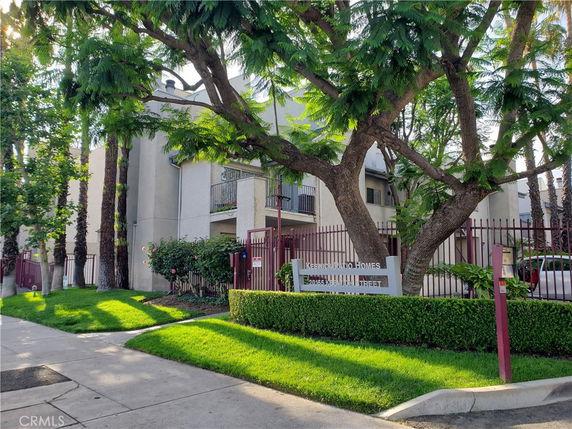 Front view of a multi-story residential building with a gated entrance.