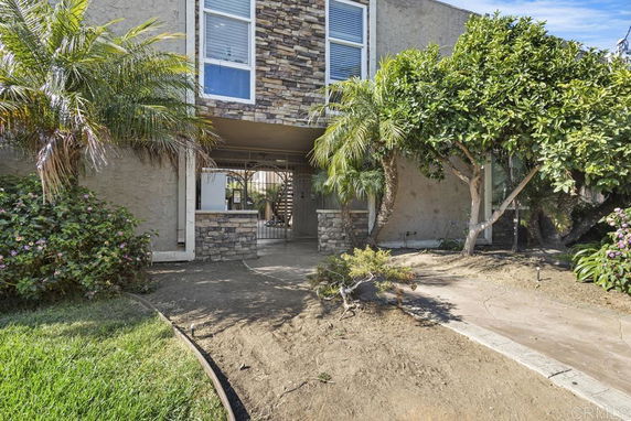 Front view of a two-story building with stone cladding and an entrance path.