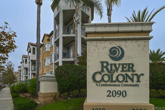Front view of a multi-story condominium building with balconies and a sign reading 'River Colony.'