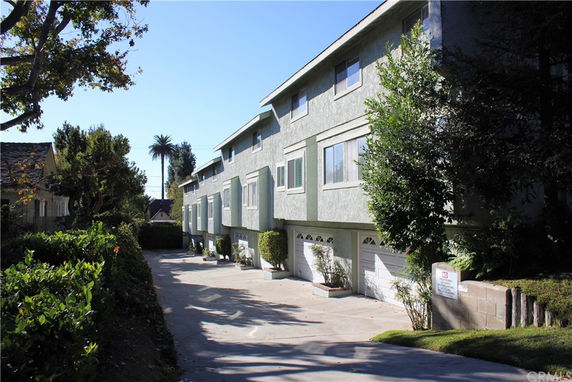 Street view of a row of multi-story townhouses with garages.