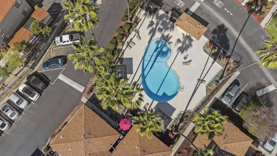 Aerial view of a swimming pool surrounded by paved areas and buildings.