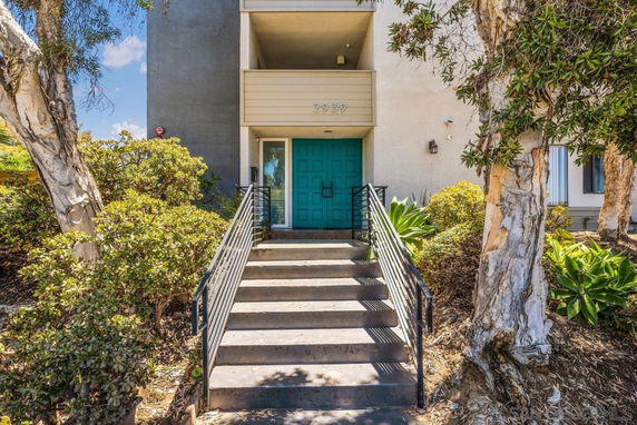 Front entrance of a building with stairs and a teal-colored door.