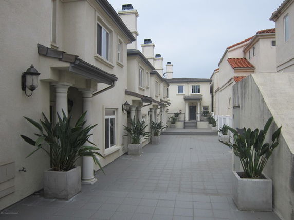 Front view of a townhouse complex with multiple units and potted plants.