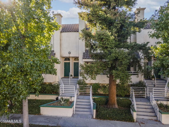 Front view of a multi-story townhouse with multiple entrances and steps leading up to the doors.