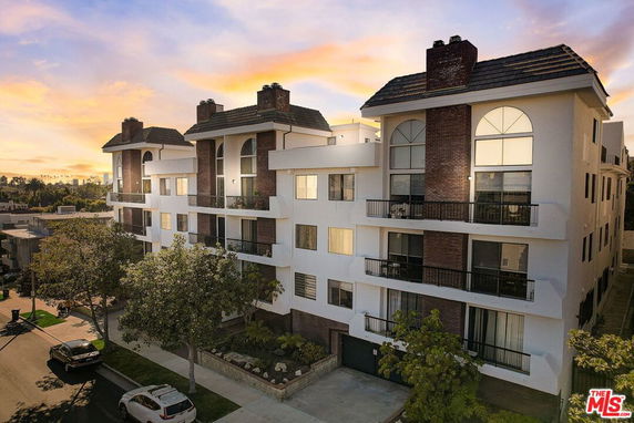 Front view of a multi-story residential building with balconies and chimneys.