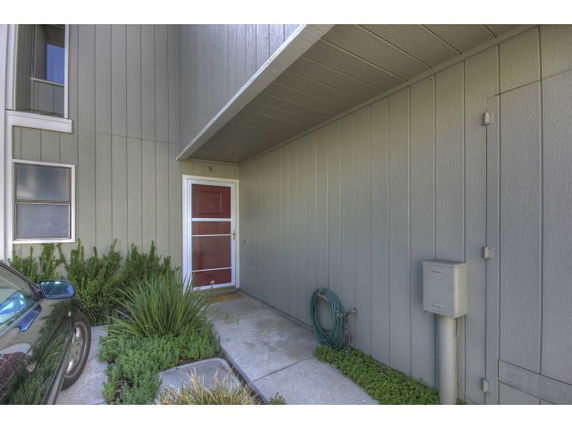 Front view of a house entrance with a small concrete path and red door.