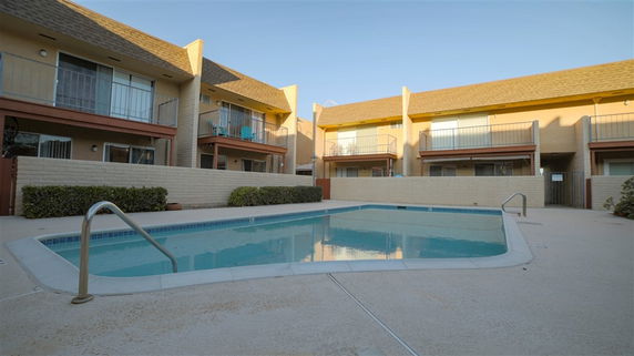 Outdoor area featuring a swimming pool surrounded by two-story residential buildings with balconies.