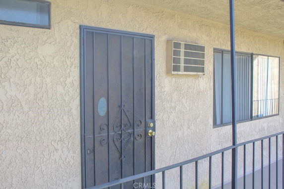 Exterior view of a building with a metal screen door, window, and air conditioning unit.