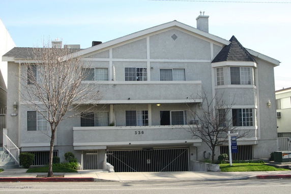 Front view of a multi-story residential building with balconies and a garage entrance.