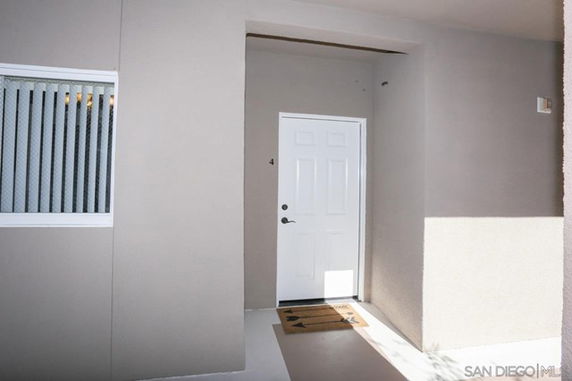 Front view of a house entrance with a white door and a doormat.