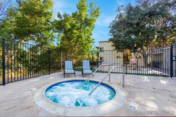 Outdoor hot tub area with fencing and lounge chairs