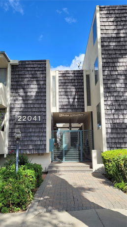 Front view of a multi-story building with shingle cladding and a gated entrance.