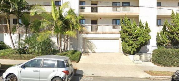 Front view of a multi-story building with balconies and a garage entrance.