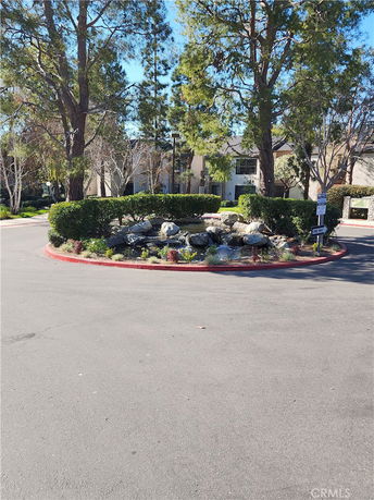 Circular landscaped area with rocks and foliage in front of a residential building.