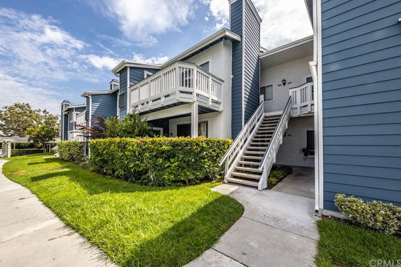 Front view of a two-story residential building with balconies and exterior stairs.