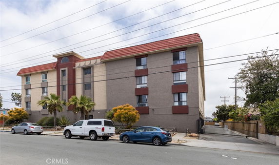 Front view of a multi-story residential building with a red-tiled roof.