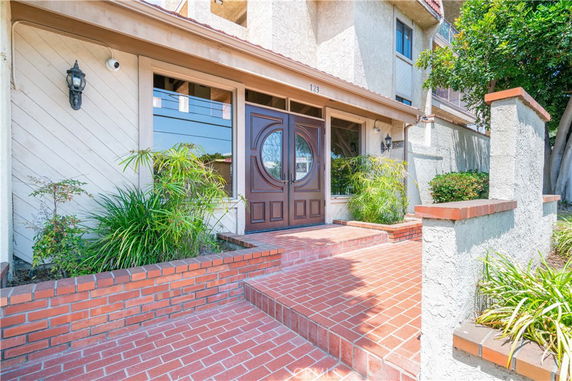 Front view of a house entrance with brick steps and double wooden door.