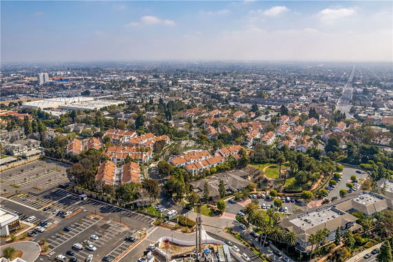 Aerial panoramic view of a residential area with multiple buildings and parking spaces surrounded by greenery.