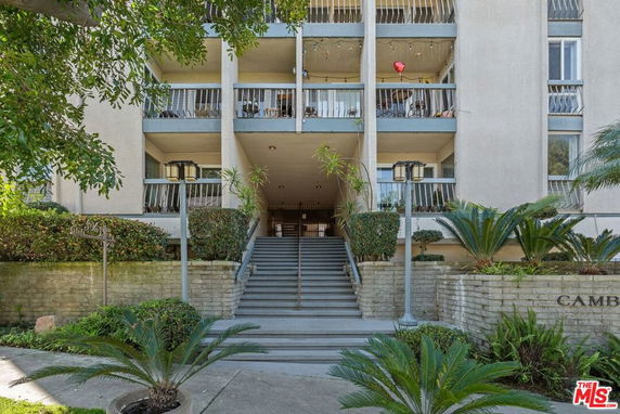 Front view of a multi-story building with balconies and a central entrance staircase.