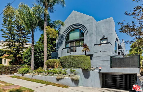 Front view of a modern multi-story house with large windows and a gated entrance.