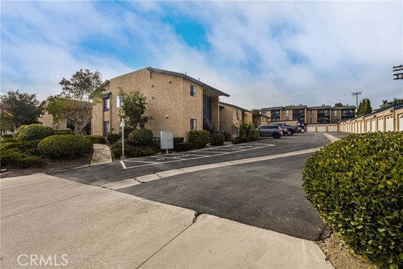 Front view of a two-story residential building with adjacent parking area.