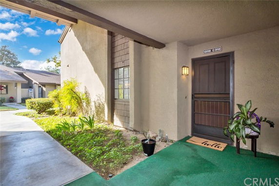 Front view of a single-story house with a covered entryway and plants.