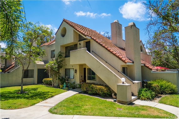 Front view of a two-story house with a red-tiled roof and an exterior staircase.
