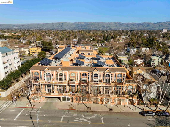 Front view of a multi-story building with large windows and solar panels on the roof.