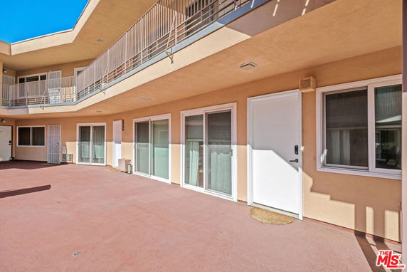 Exterior view of a residential building with multiple sliding glass doors and a balcony with metal railings.