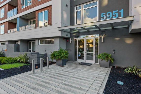 Front view of a modern multi-story building entrance with glass doors and signage.