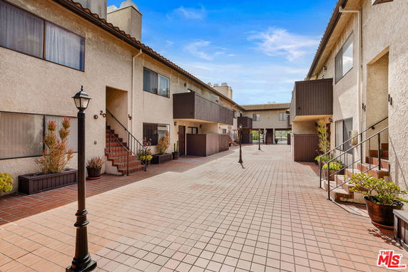 View of the exterior walkway and courtyard of a multi-story residential building.