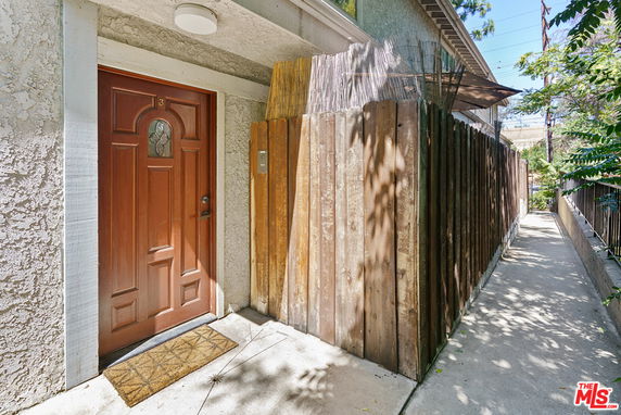 Front view of a house entrance with a wooden door and adjacent wooden fence.