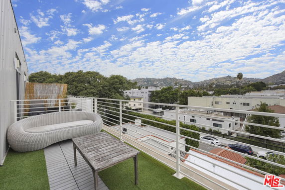 Rooftop deck with outdoor seating offering a panoramic view of the surrounding area and hills.