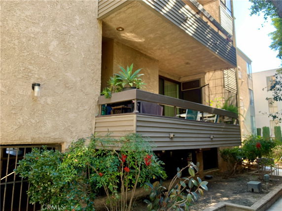 Side view of a multi-story building with balconies and foliage.