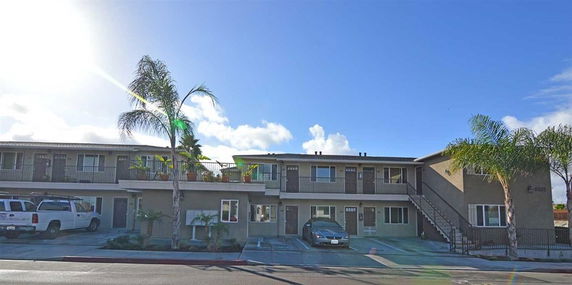 Front view of a two-story apartment building with parking spaces.