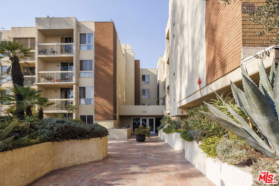 Front view of a multi-story residential building with balconies and a central entrance.