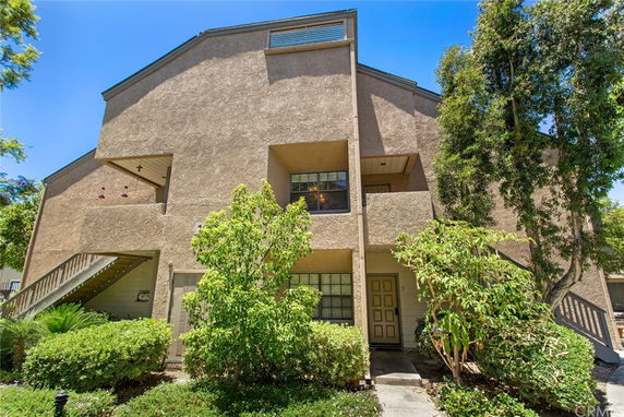 Front view of a multi-level residential building with an entrance and stairs.