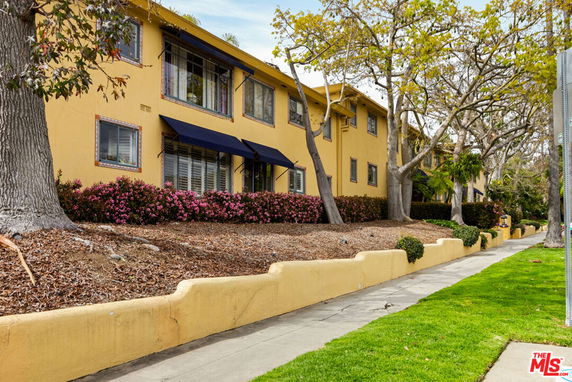 Front view of a two-story building with yellow exterior and blue awnings.
