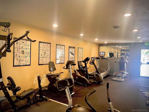 Interior view of a gym with exercise equipment and instructional posters.