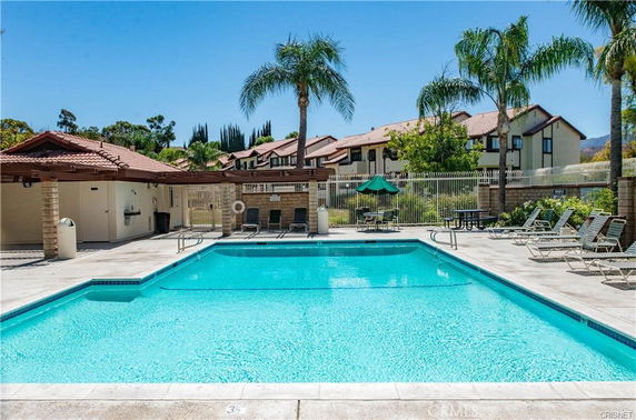 Outdoor swimming pool area with seating and umbrellas.