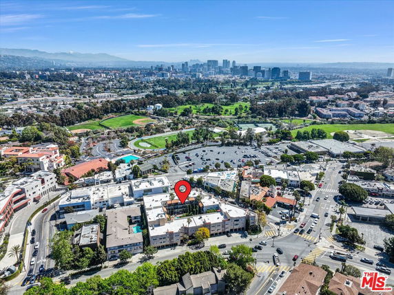 Aerial view of a cityscape with various buildings, roads, and green areas in the background.