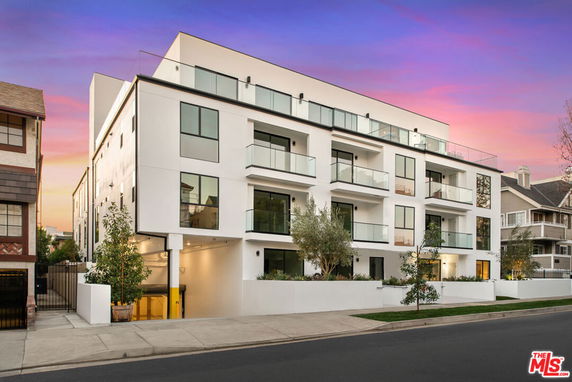 Front view of a modern multi-story apartment building with large windows and balconies.