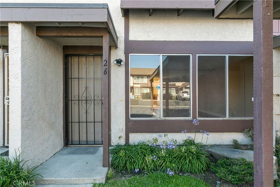 Front view of a townhouse entrance with a metal security door and large window.